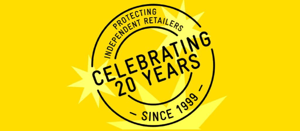 A circular black stamp on a yellow background reads Protecting Independent Retailers, Celebrating 20 Years, and Since 1999, with starburst accents behind the text.