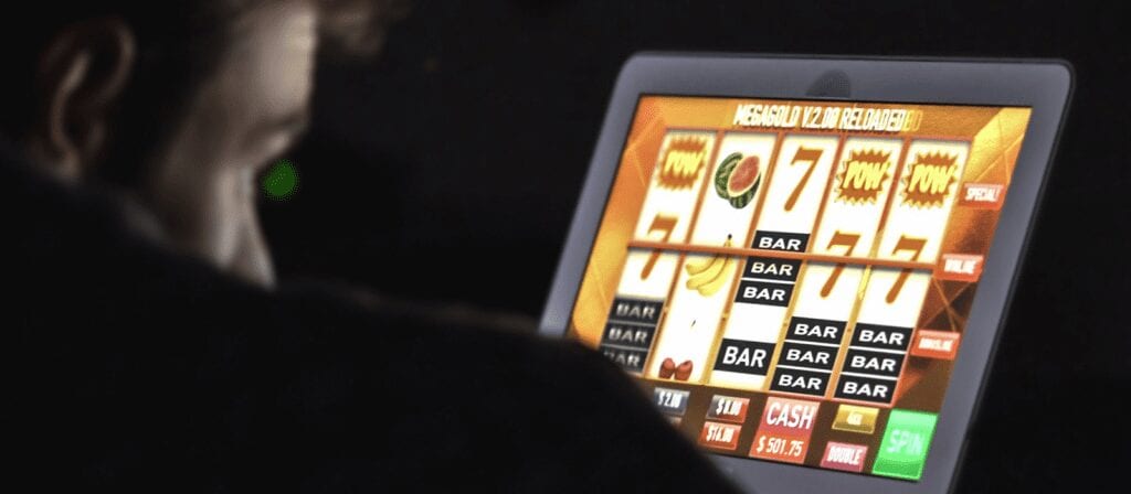 A person plays a digital slot machine on a touchscreen, displaying spinning reels with symbols like 7s, BARs, and cherries. The screen shows a winning combination and a cash prize.