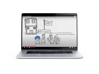 A laptop displays a cartoon video with hand-drawn characters standing in front of a building, a sign, and text in German. The video uses a simple black-and-white style with some blue highlights.