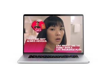 A laptop screen displays a woman with bangs and text that reads, Their care isnt always obvious. Like protecting the family with a life insurance plan. An image of a man holding a heart appears in the background.