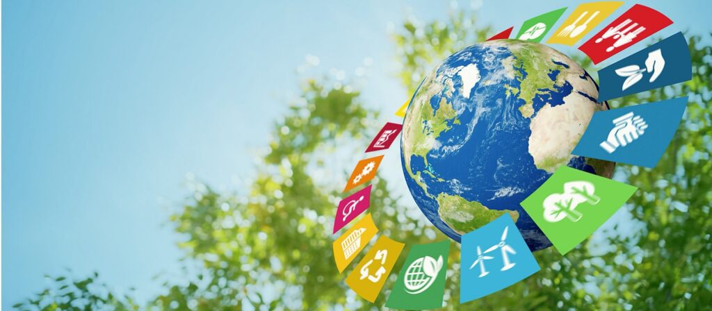 A globe floats in the sky with green trees in the background, surrounded by colorful icons representing the United Nations Sustainable Development Goals.