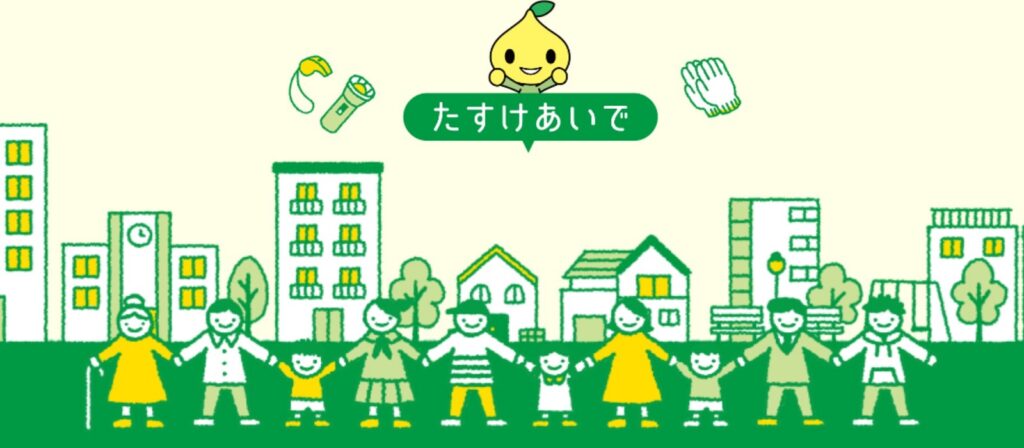 Illustration of diverse people holding hands in front of buildings and houses, a smiling yellow mascot above them, and Japanese text in a green speech bubble. Safety items like a flashlight and gloves are shown above.