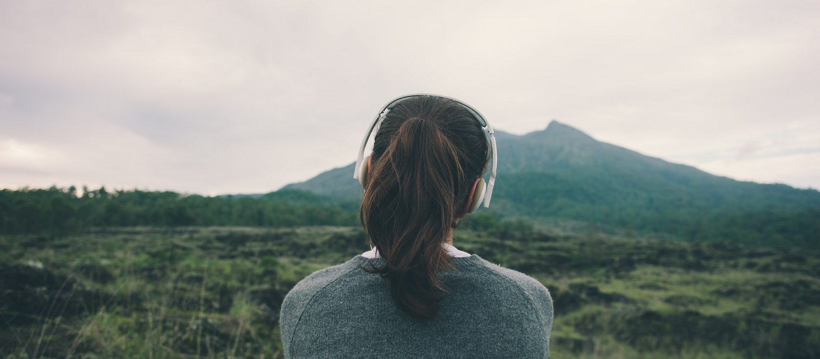 Woman in headphones listening music in nature and at the mountai