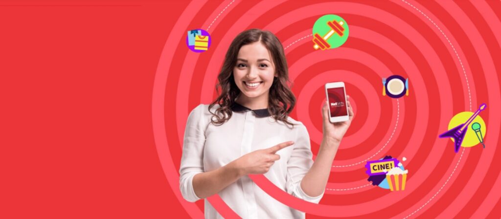 A smiling woman points to a smartphone she is holding, with colorful icons like popcorn, gifts, and a gavel on a red background with spiral patterns.
