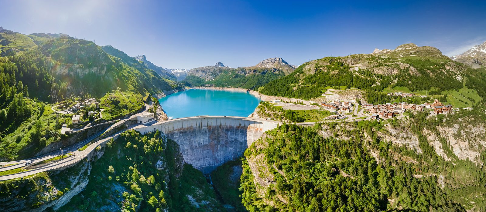 Water dam and reservoir lake aerial panoramic view in French Alps mountains generating hydroelectricity. Low CO2 footprint, decarbonize, renewable energy, sustainable development. Hydro power.