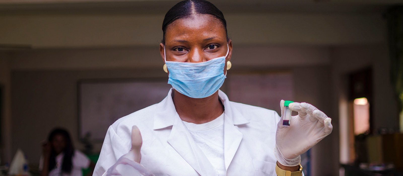 young beautiful african doctor wearing face mask holding vaccine, cure of the outbreak in the society