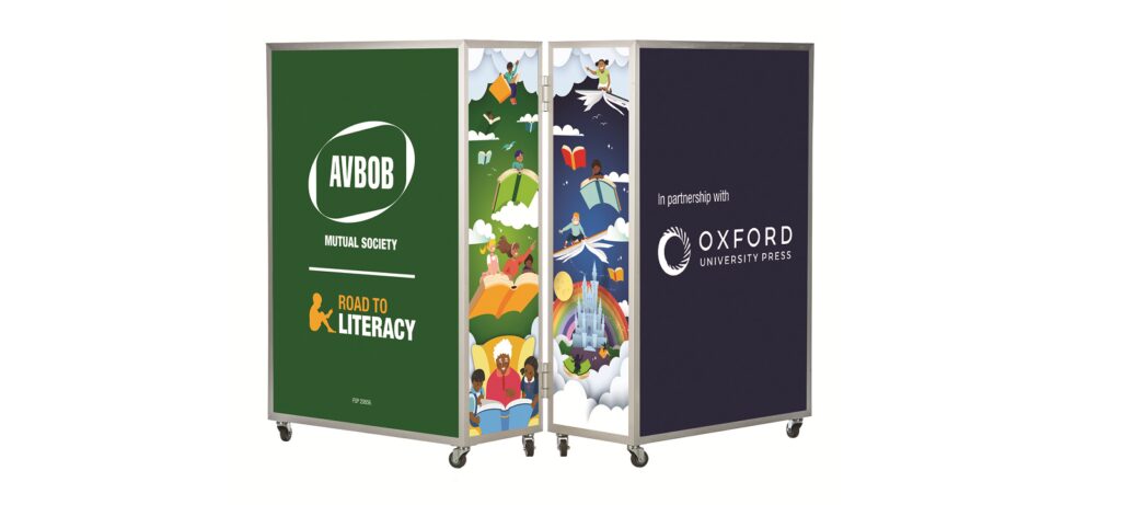 Three moveable display panels: one green with AVBOB Mutual Society Road to Literacy, one with colorful illustrations of books and children, and one dark blue with In partnership with Oxford University Press.