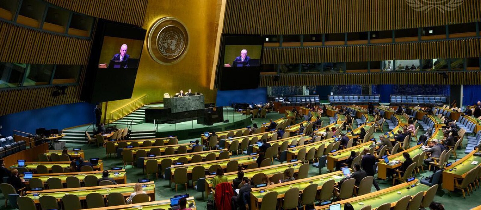 Csaba Kőrösi (left at dais and on screens), President of the seventy-seventh session of the United Nations General Assembly, chairs the 66th plenary meeting of the General Assembly.