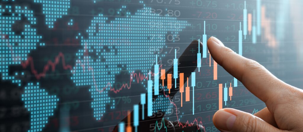 A hand points to a virtual screen displaying colorful financial charts, graphs, and numbers overlaid on a world map, representing global stock market data and trading activity.