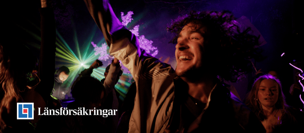 A joyful young man dances with raised arms at a vibrant party with colorful lights and people in the background. The Länsförsäkringar logo and name appear in the lower left corner.