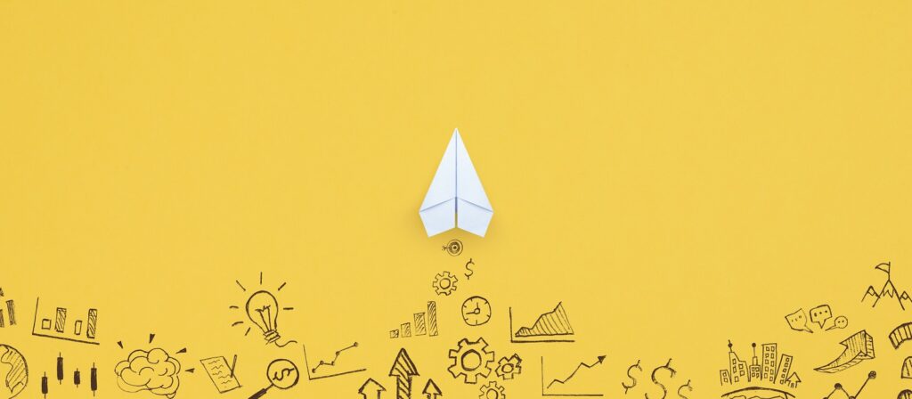 A white paper airplane is centered on a bright yellow background, surrounded by black doodles of business symbols such as graphs, gears, light bulbs, and arrows.