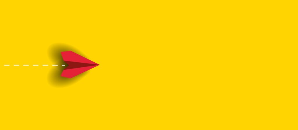 A red paper airplane with a dotted white trail flies to the right on a bright yellow background, casting a shadow to the left.
