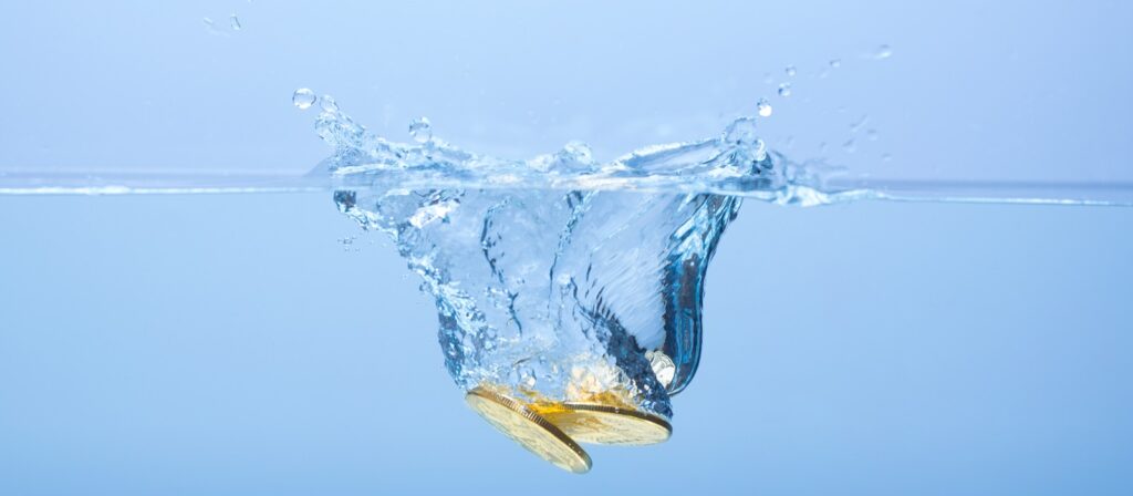 Three gold coins splash into clear water, creating ripples and bubbles against a light blue background.