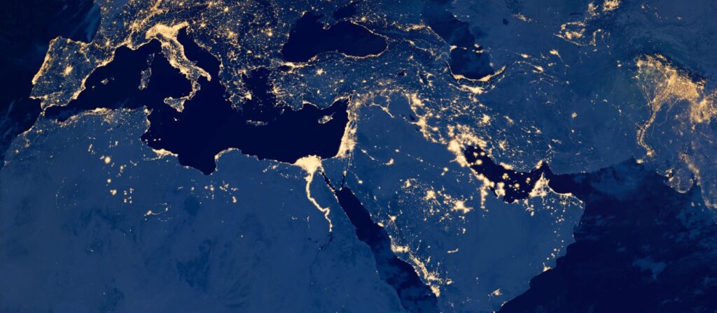 Satellite image showing the Middle East, parts of Europe, and North Africa at night, with city lights illuminating populated areas along coastlines and rivers. The Mediterranean Sea is dark and clearly visible.